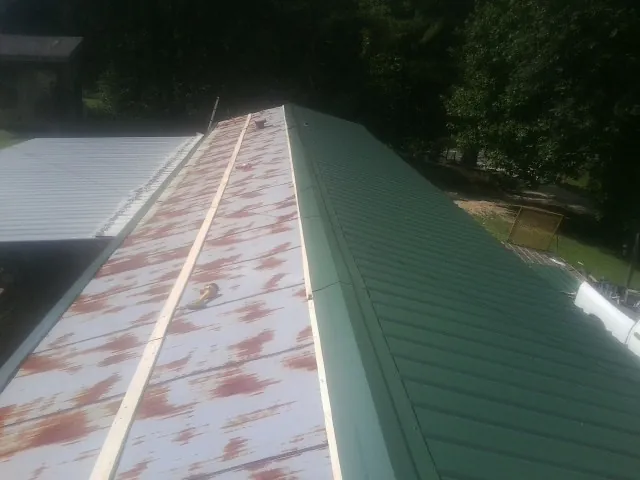 Old rusted panels beside newly installed green metal roofing — Wind Damage Roof Repair by Roofing Brothers in Pottstown