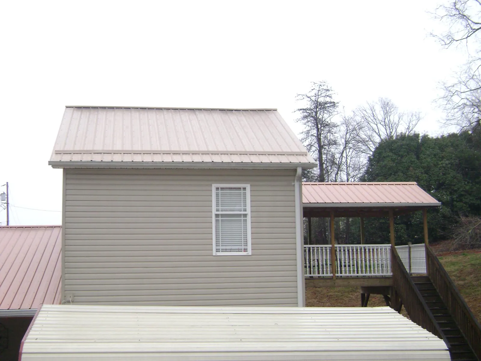 Tan metal roofs on a two story addition and attached porch, from a Roof Replacement job in Pottstown