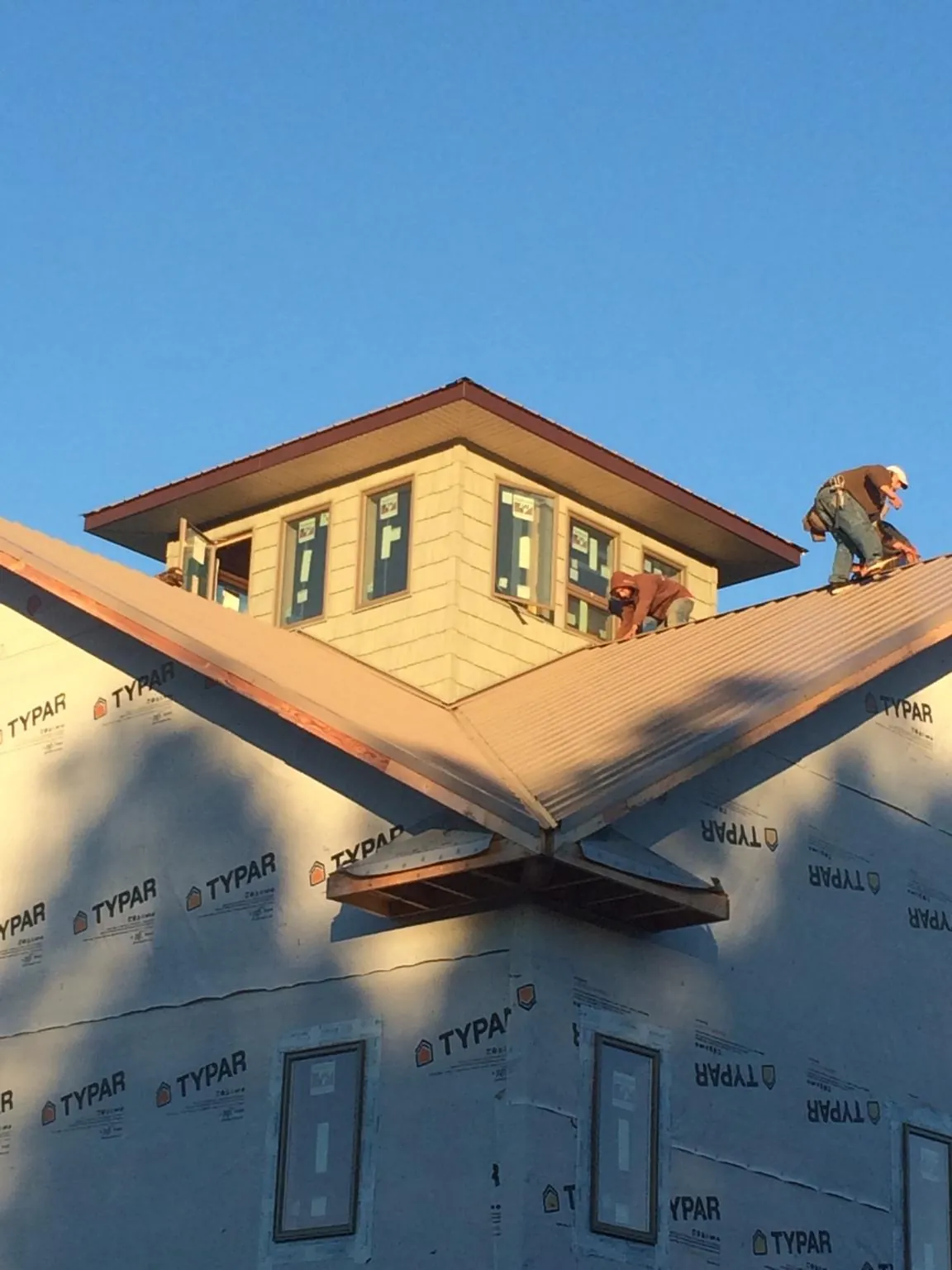Roofers working around a rooftop cupola on a new metal roof at sunset — Roof Waterproofing in Pottstown by Roofing Brothers